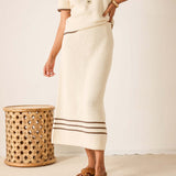 Person wearing a cream-colored skirt with a subtle pattern, standing against a plain background.