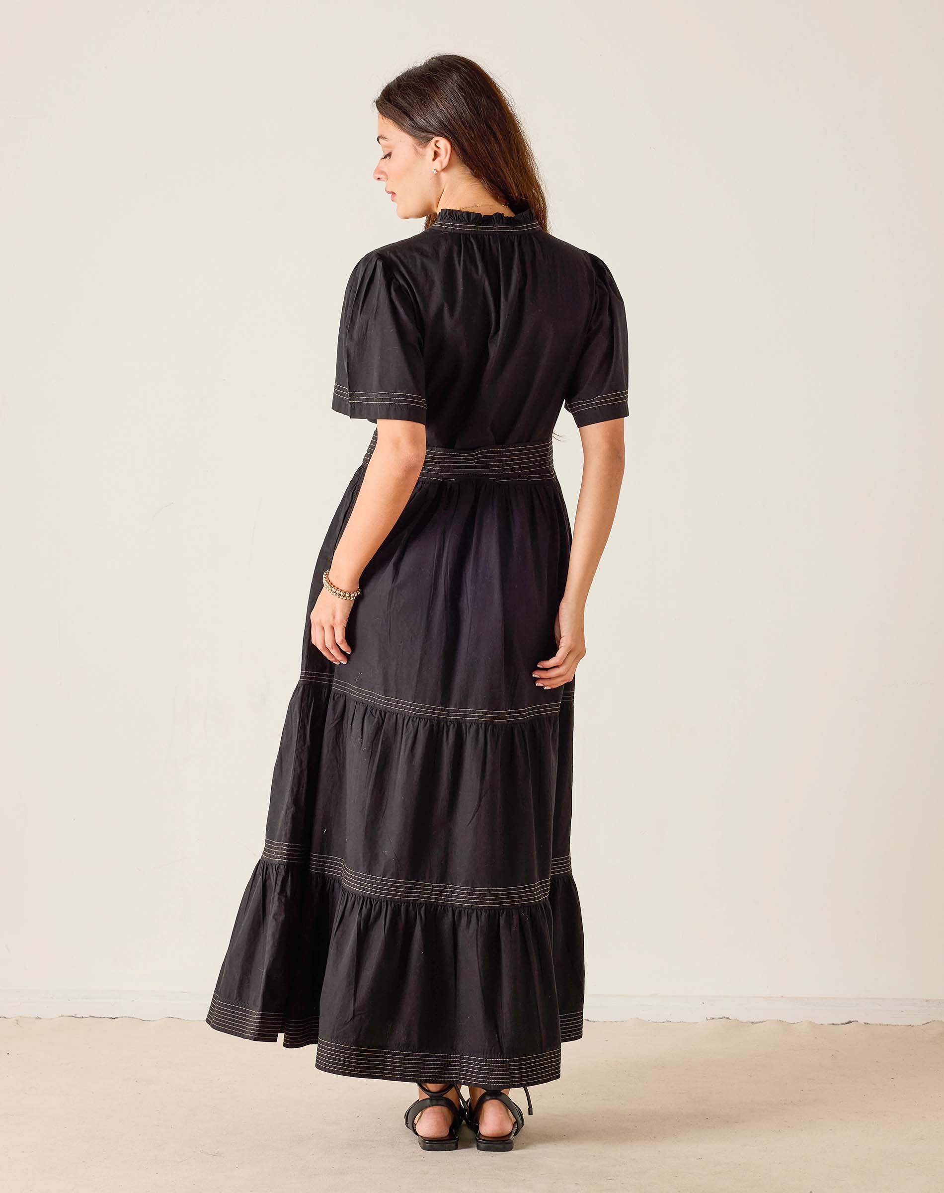 Woman wearing a black dress with white trim on a beige background