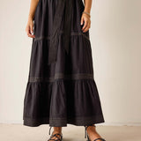 Person wearing a black tiered dress with a plain background