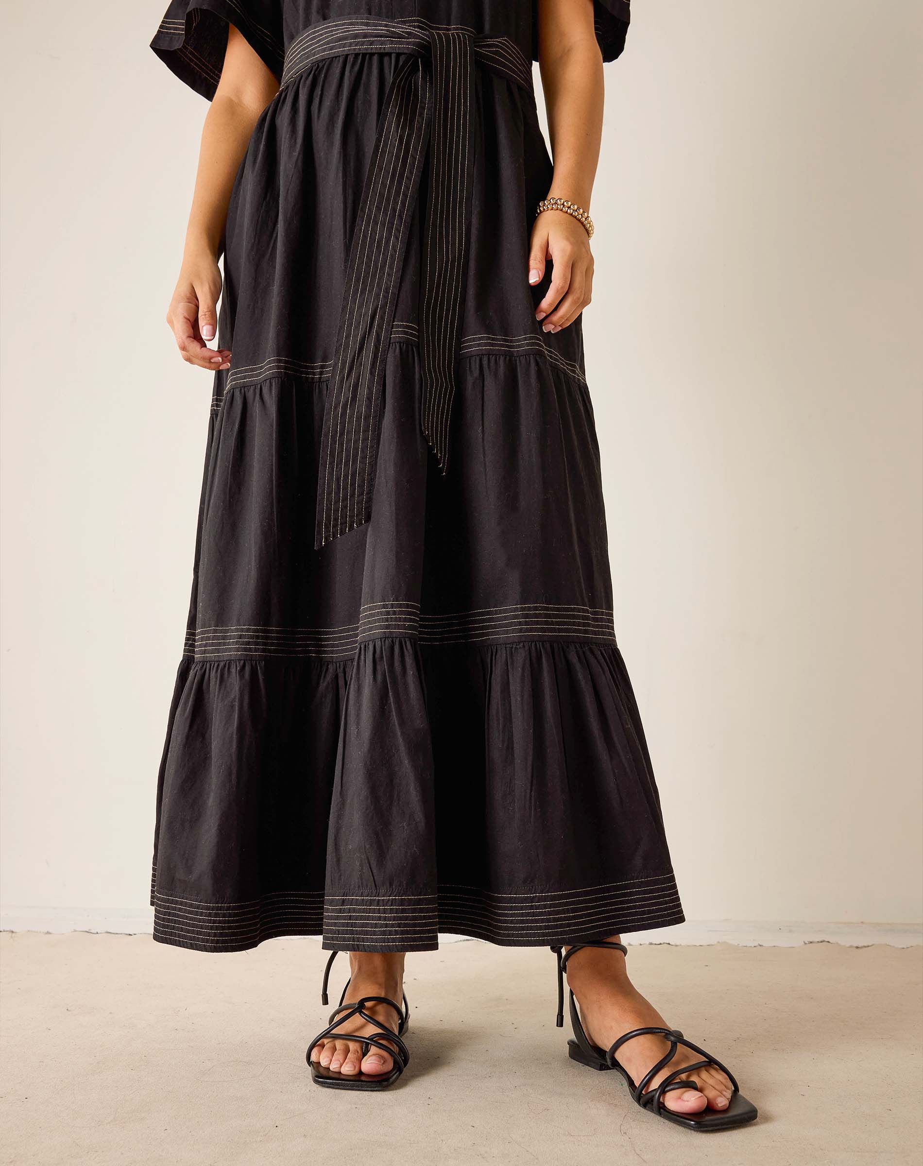 Person wearing a black tiered dress with a plain background
