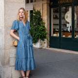 Woman in a blue dress standing outside a building with 'Chocolat' sign.