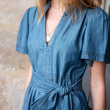 Woman wearing a blue dress with a stone wall background