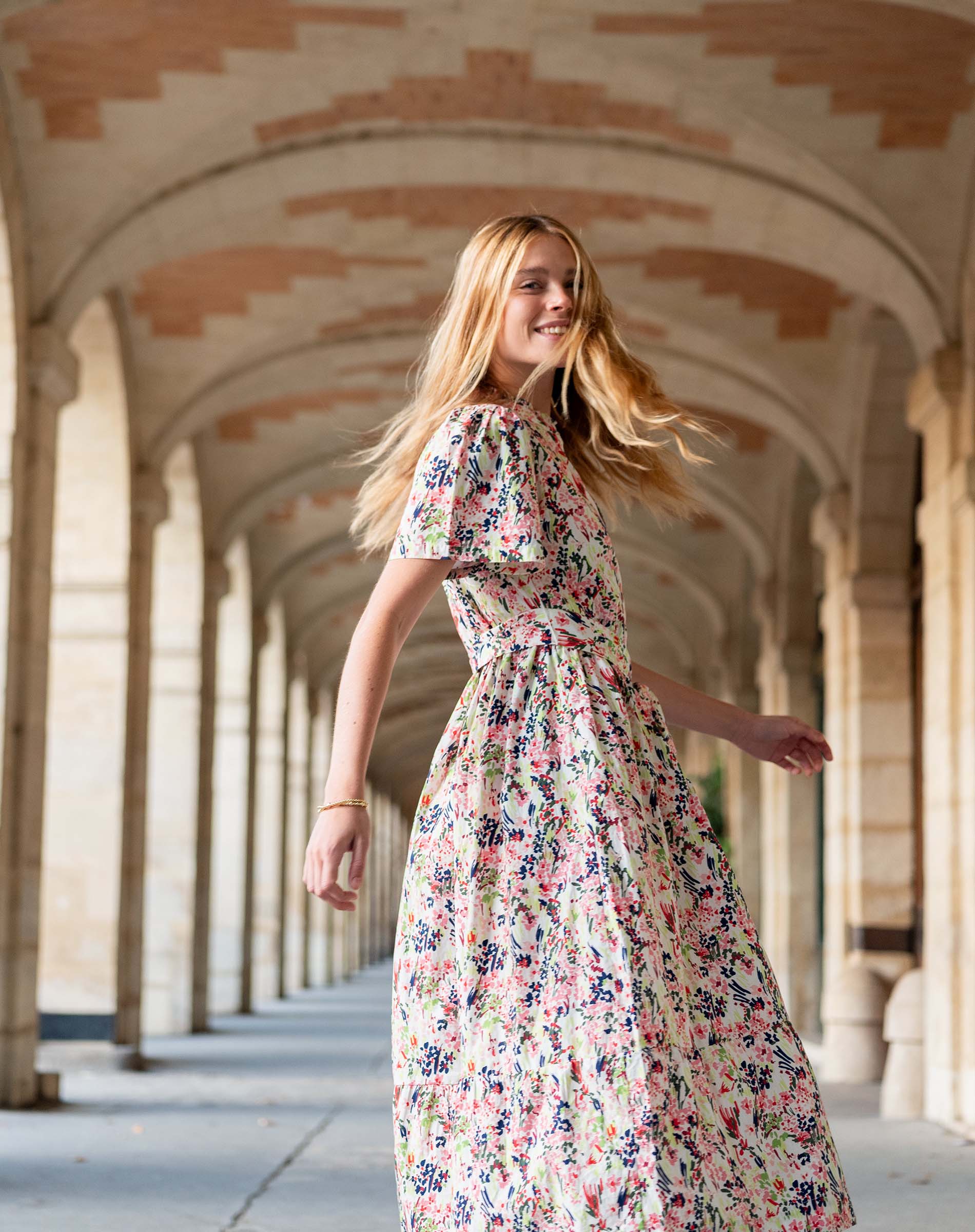 Woman in a floral dress walking through an archway