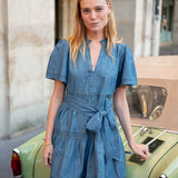 Woman in a blue dress standing next to a vintage car