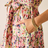 Multicolored floral dress with a hand in the pocket against a neutral background