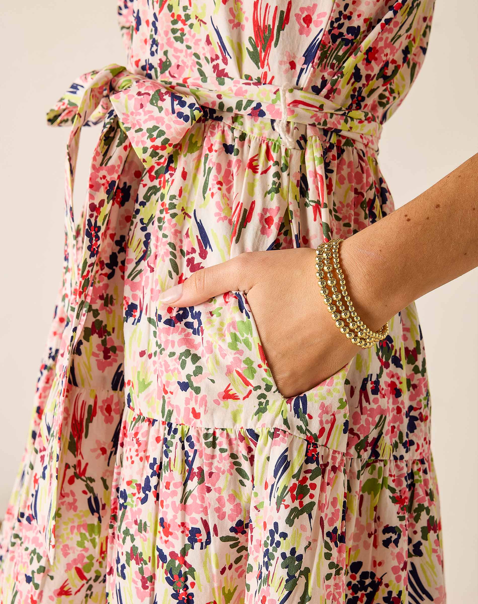 Multicolored floral dress with a hand in the pocket against a neutral background