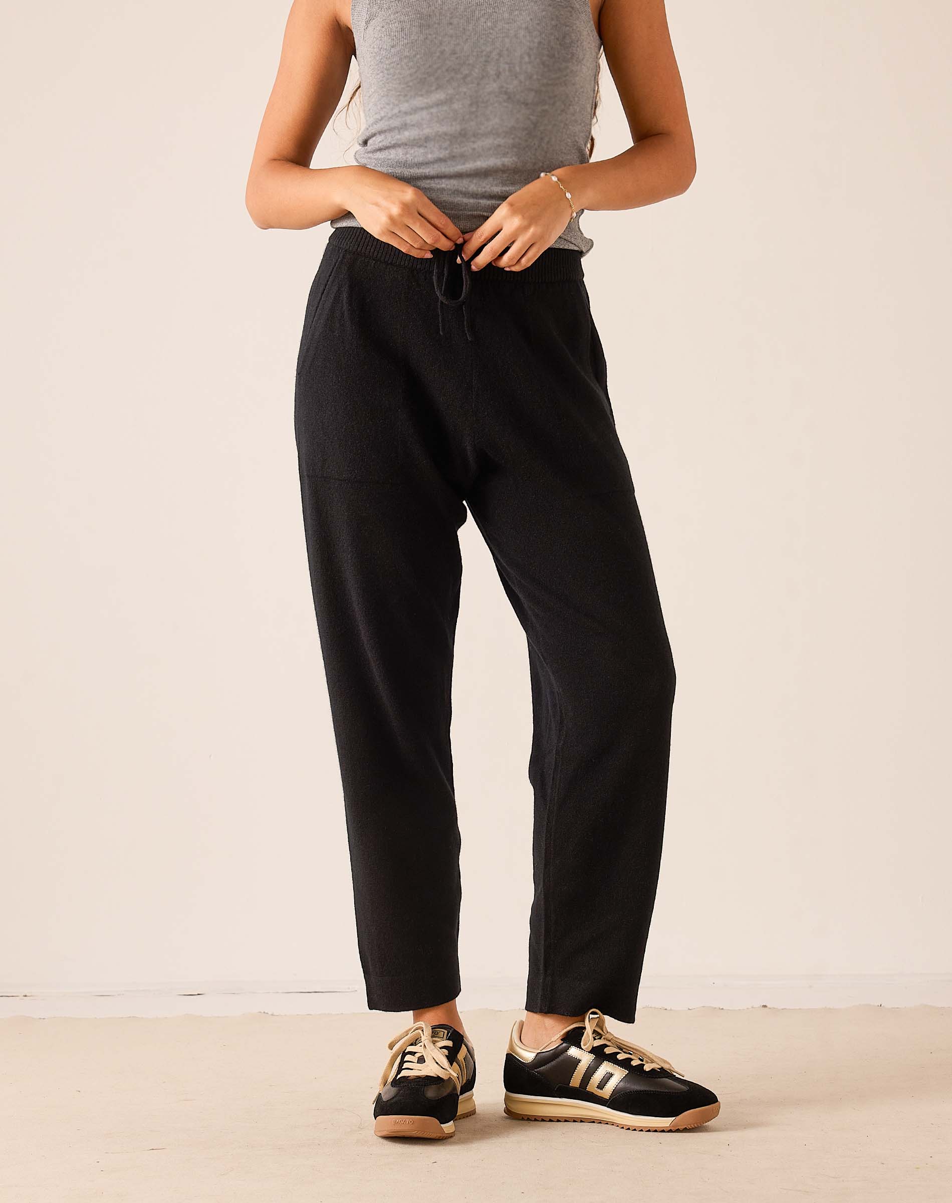 Black tapered cashmere pants with an elastic drawstring waist and relaxed fit.