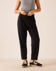 Black tapered cashmere pants with an elastic drawstring waist and relaxed fit.
