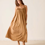 Woman wearing a long brown dress against a plain background