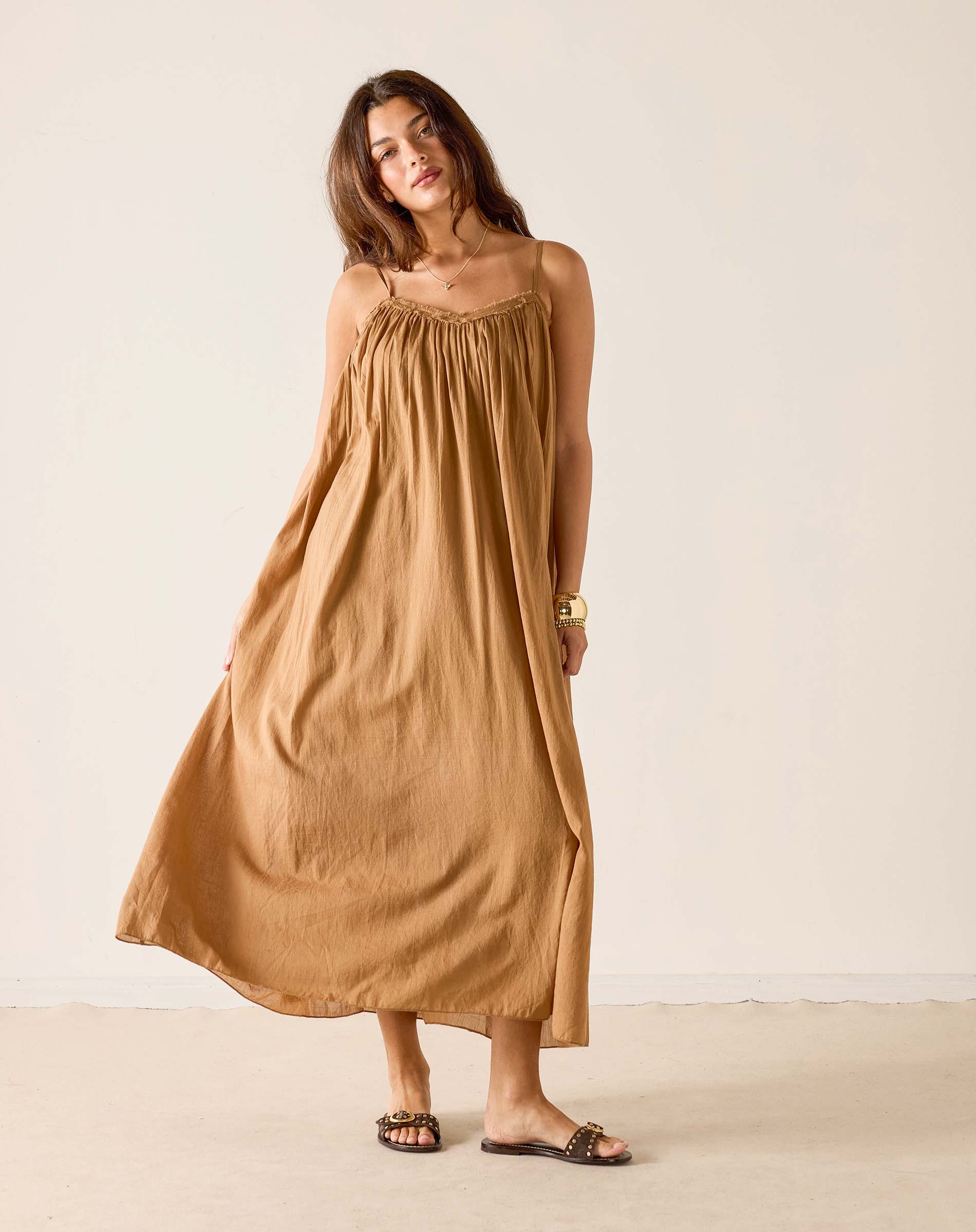 Woman wearing a long brown dress against a plain background