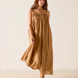 Woman wearing a long brown dress against a plain background