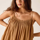 Woman wearing a brown dress with thin straps against a beige background