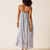 Woman wearing a light gray maxi dress against a plain background