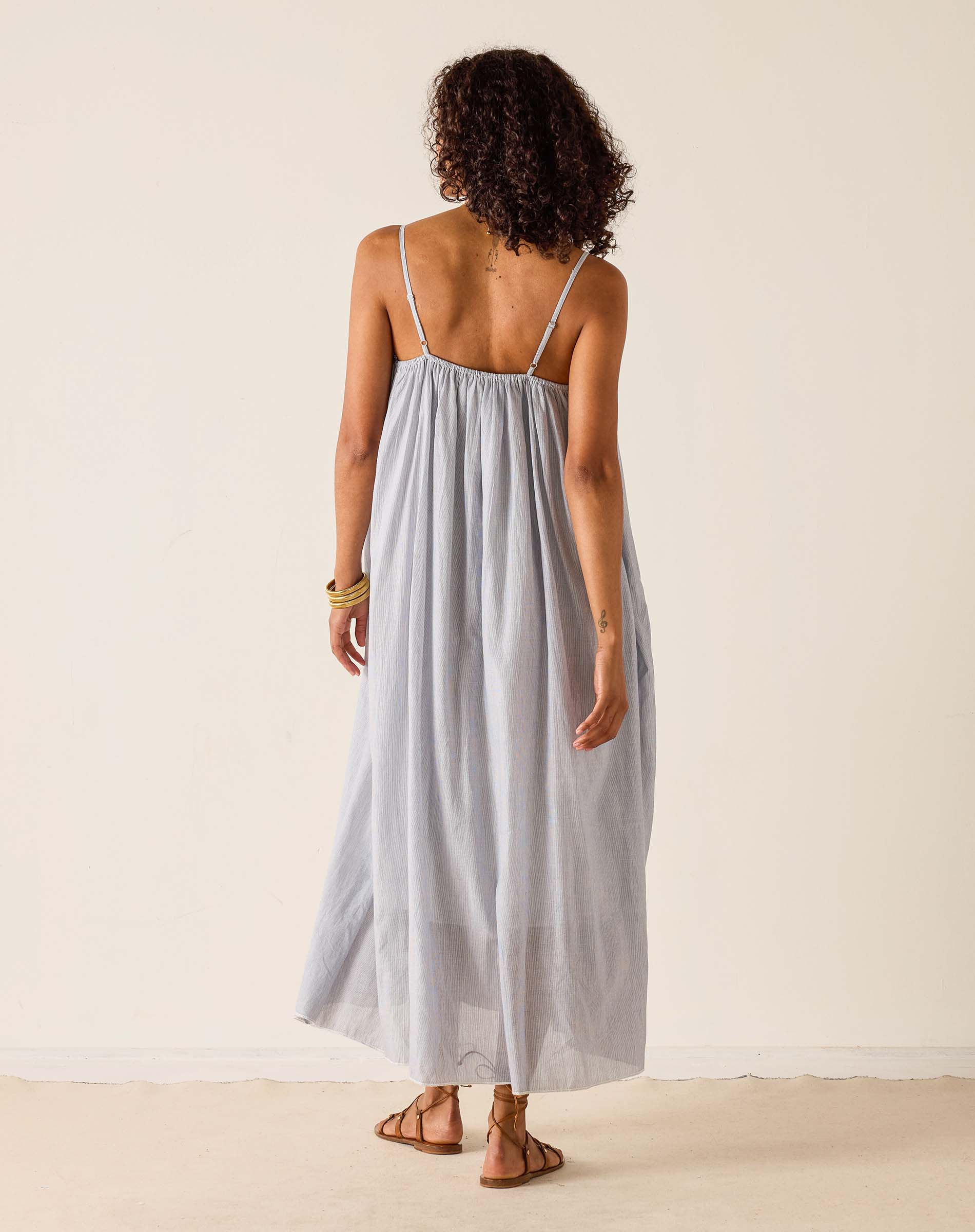 Woman wearing a light gray maxi dress against a plain background