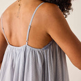 Woman wearing a light gray dress with thin straps on a neutral background