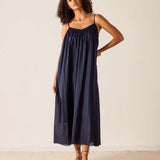 Woman wearing a navy slip dress against a plain background