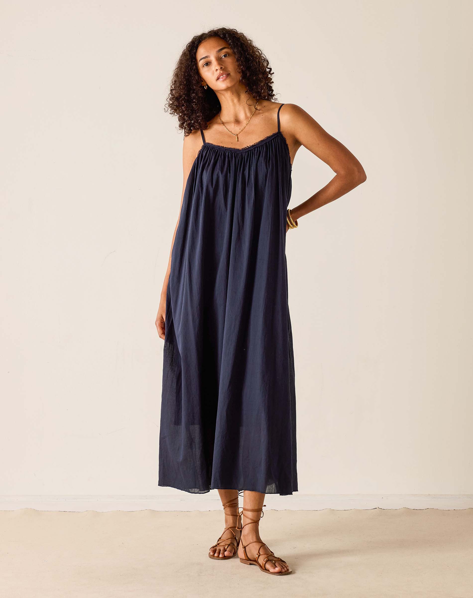 Woman wearing a navy slip dress against a plain background