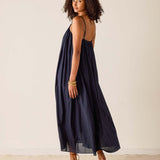 Woman wearing a navy blue dress with a backless design against a plain background