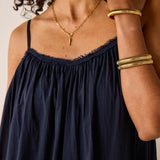 Navy blue dress with gold jewelry on a neutral background