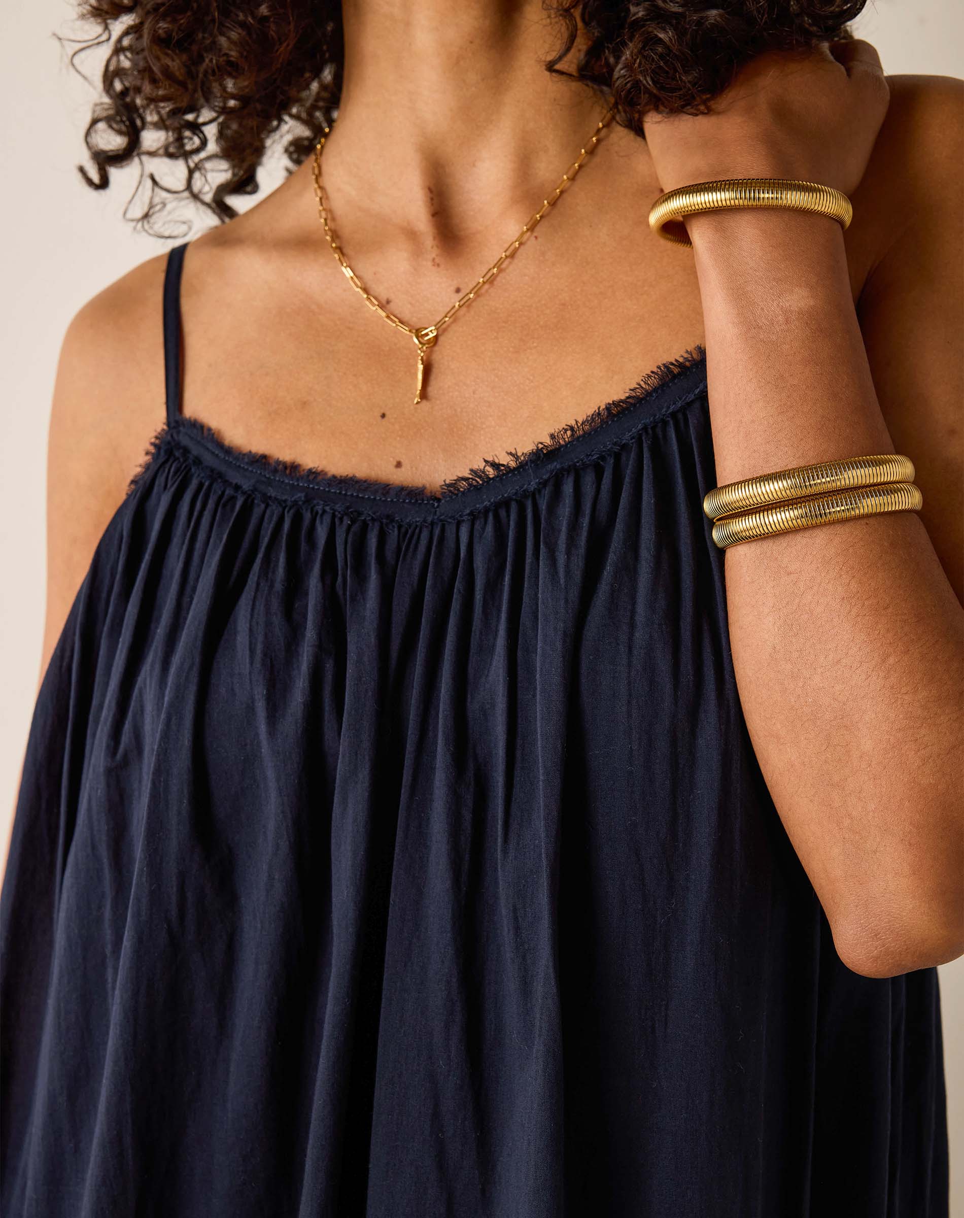 Navy blue dress with gold jewelry on a neutral background