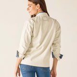 Woman wearing a beige jacket and blue jeans on a plain background