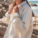 Woman wearing a beige coat on a beach