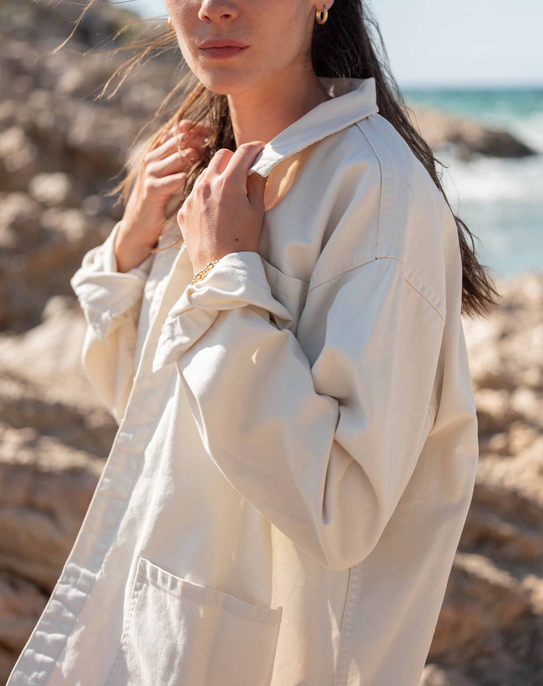 Woman wearing a beige coat on a beach
