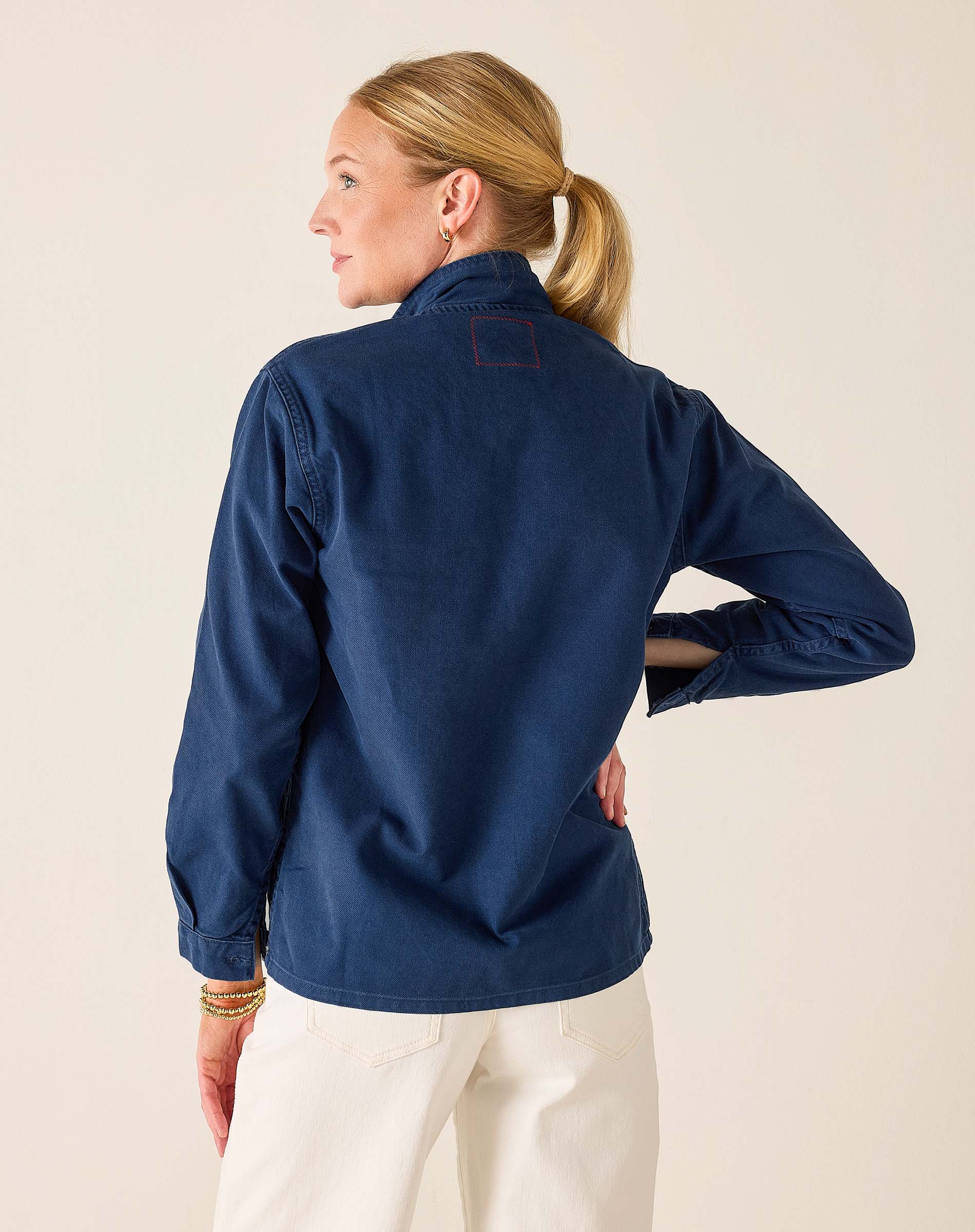Woman wearing a navy blue shirt with a beige background