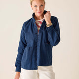 Woman wearing a blue jacket over a striped shirt with a neutral background