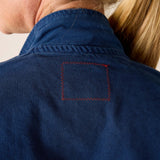 Close-up of a person wearing a blue jacket with a red-stitched pocket.