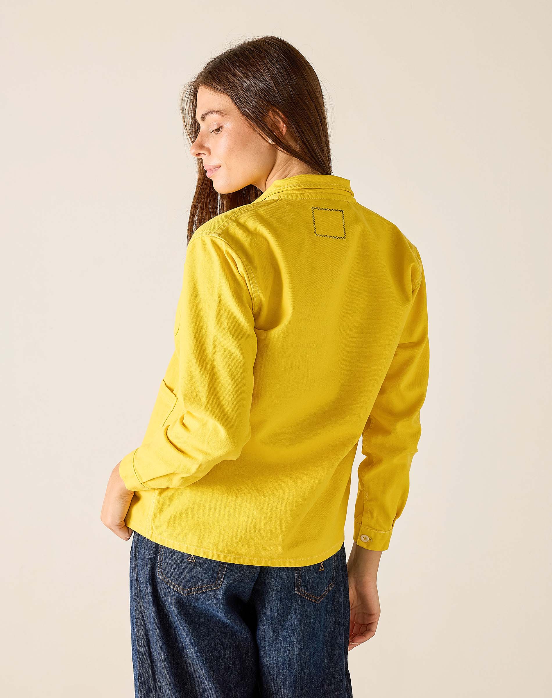 Woman wearing a yellow jacket on a beige background