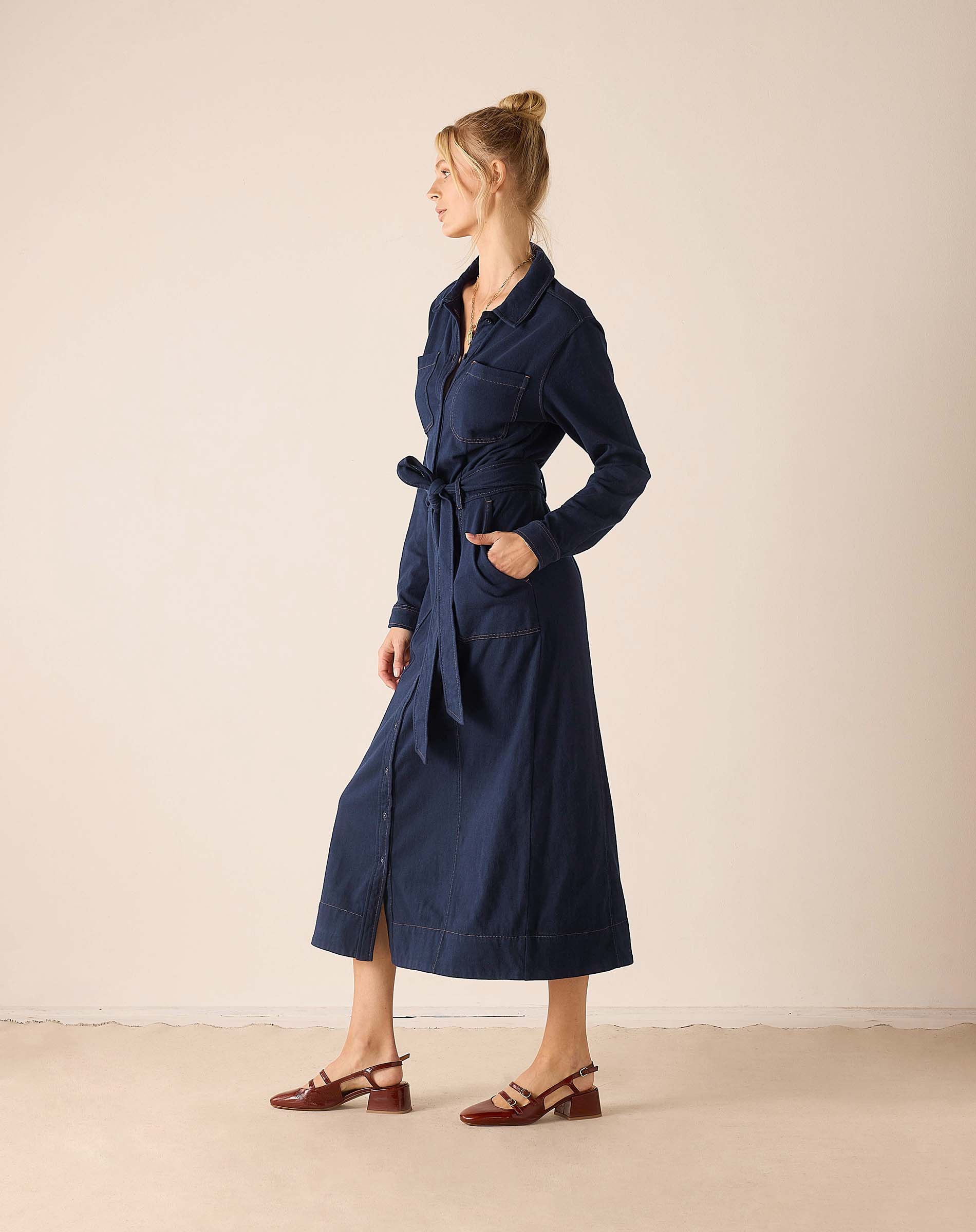 Navy blue utility dress with a wrap-around waist tie and long sleeves.