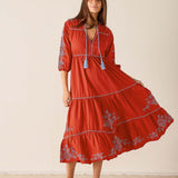 Woman wearing a red dress with floral embroidery on a beige background