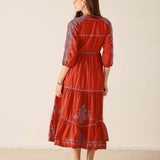 Woman wearing a red dress with floral patterns on a beige background