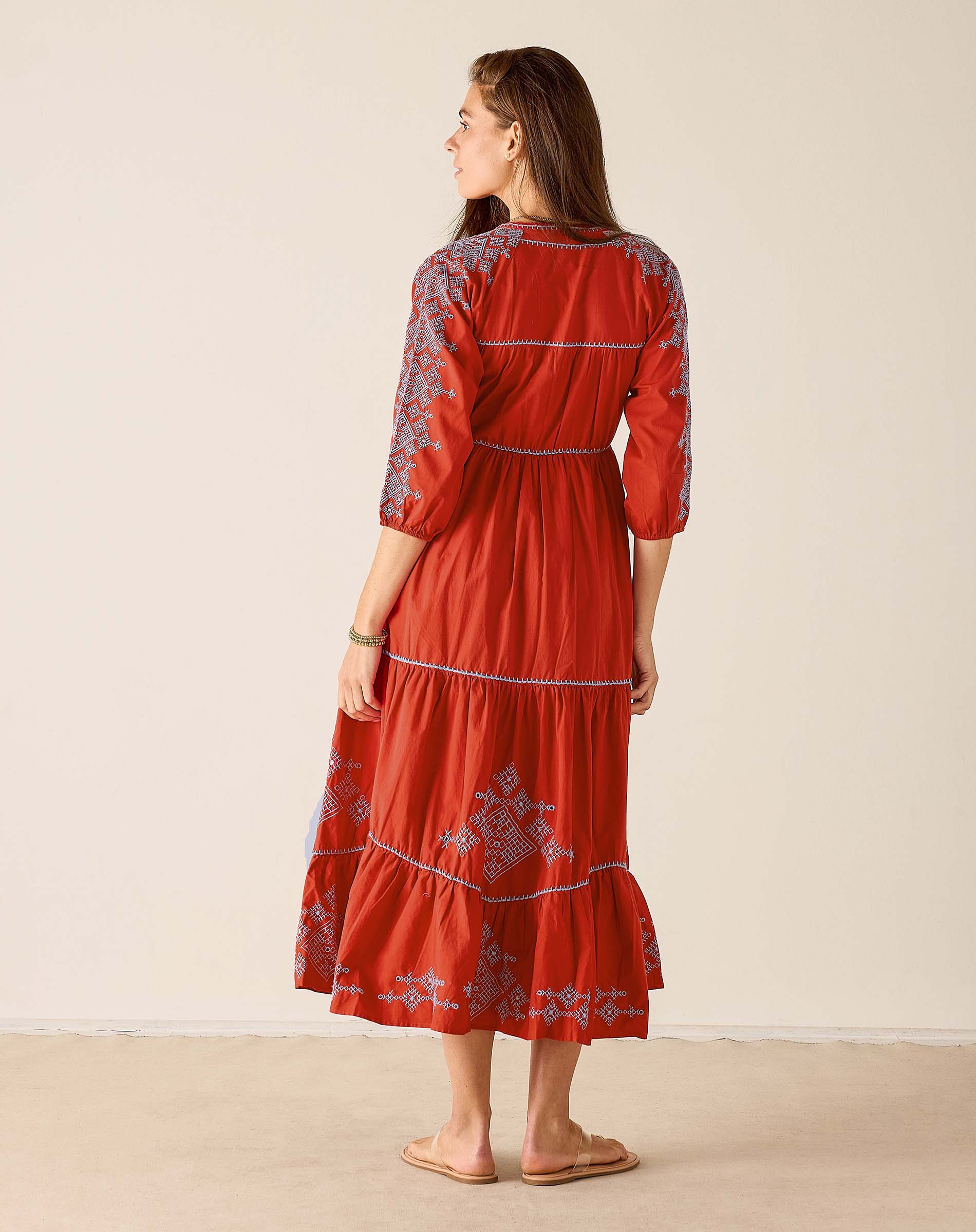 Woman wearing a red dress with floral patterns on a beige background