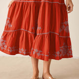 Red embroidered dress worn by a person on a beige background