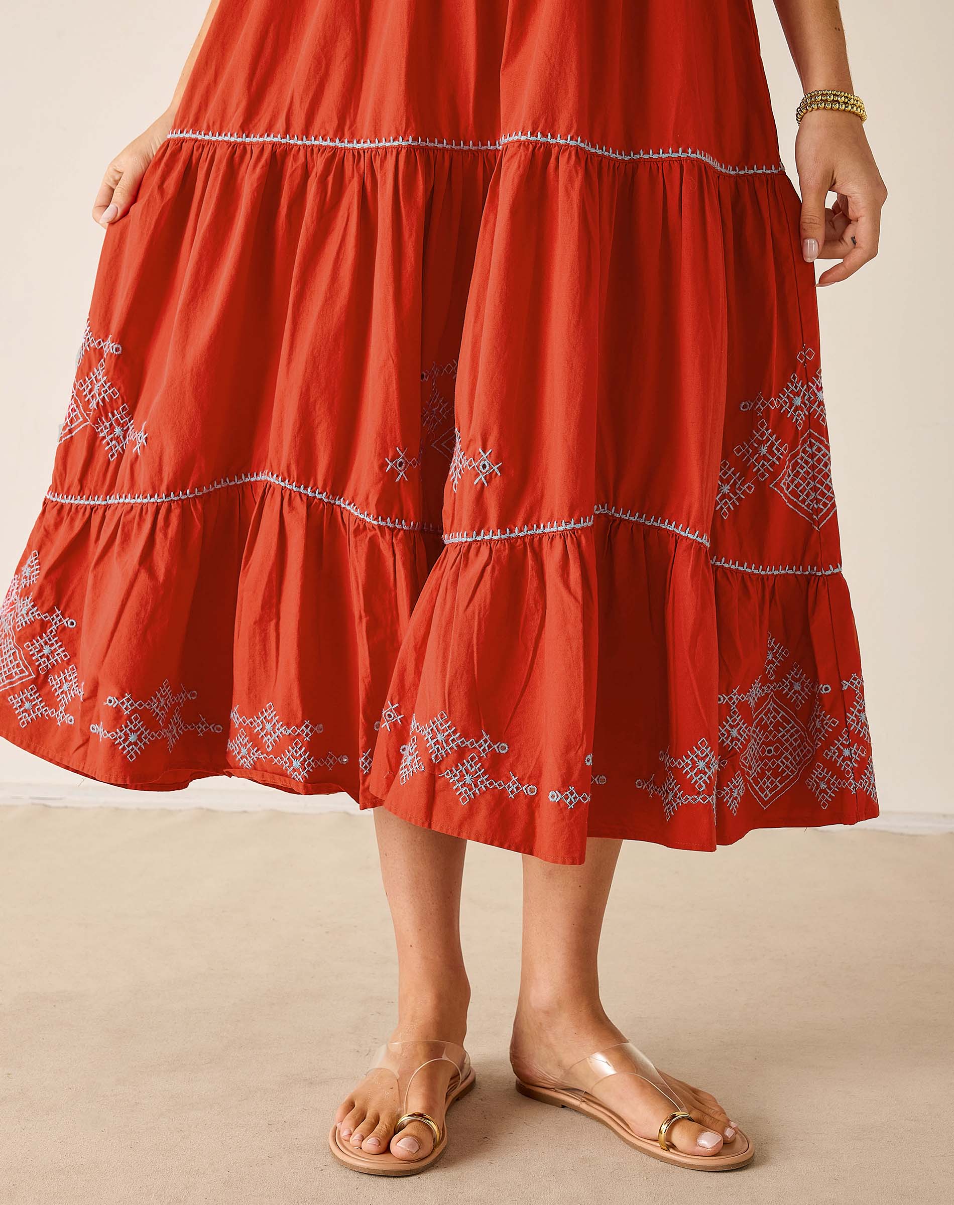 Red embroidered dress worn by a person on a beige background