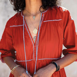 Person wearing a red dress with white embroidery against a neutral background