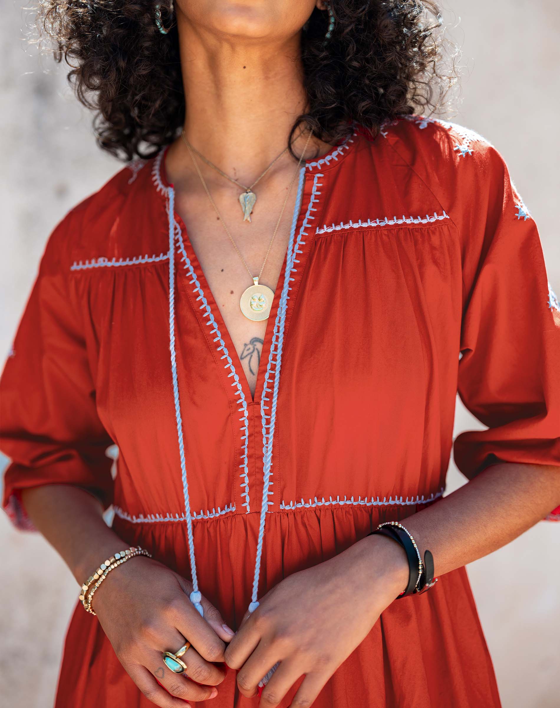 Person wearing a red dress with white embroidery against a neutral background