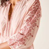 Light pink blouse with red embroidery on a plain background