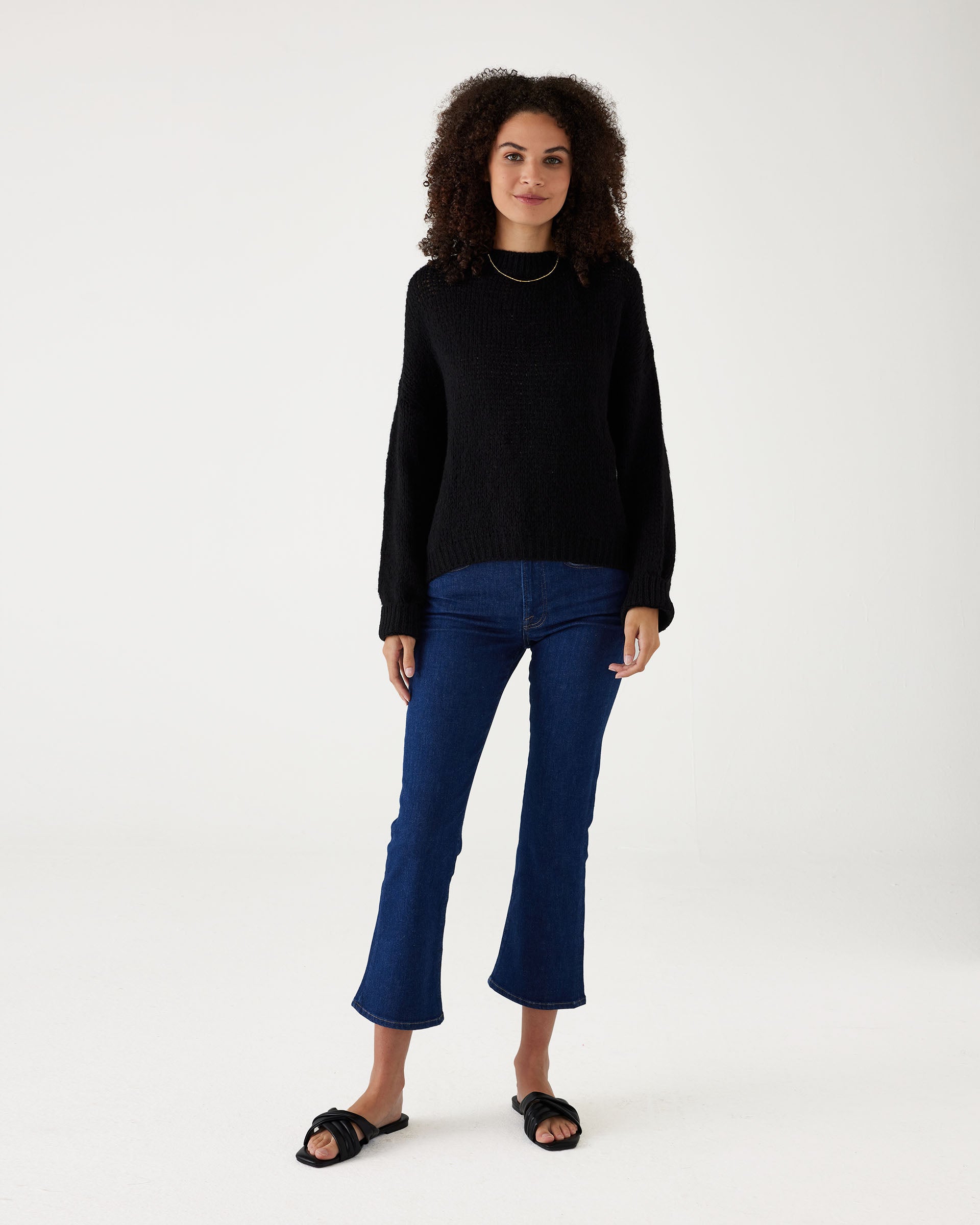 woman wearing mersea pisa sweater in black standing against white background