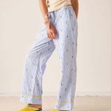 Person wearing blue striped pajama pants with yellow trim on a beige background