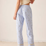 Person wearing light blue striped pajama pants with a subtle pattern on a plain background
