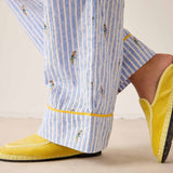 Person wearing blue and white striped pants with yellow trim and yellow shoes on a beige background