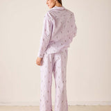 Woman wearing a matching pajama set with a light purple background