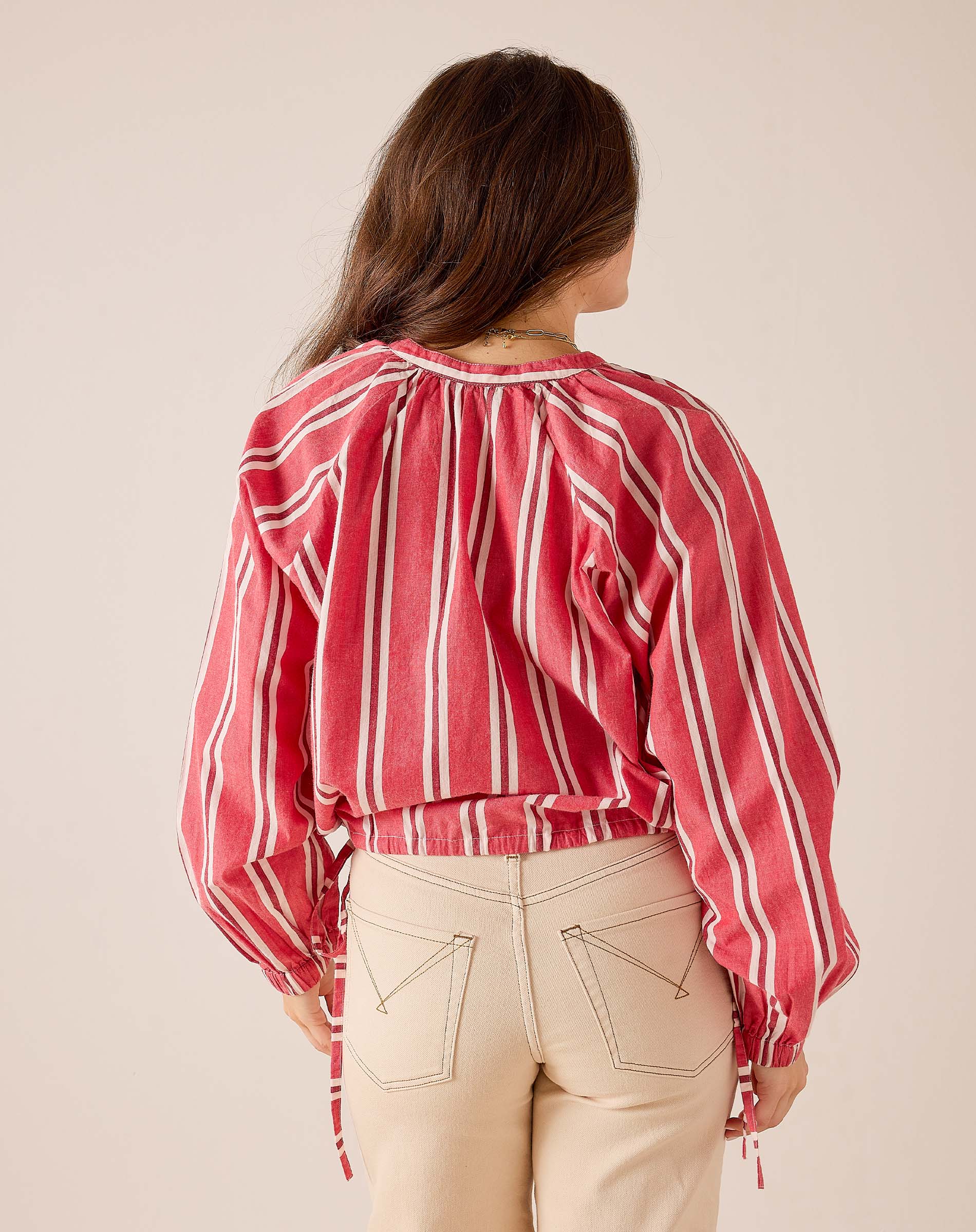 Back view of women's travel-friendly red and white striped poet top with voluminous sleeves and elasticated waist.