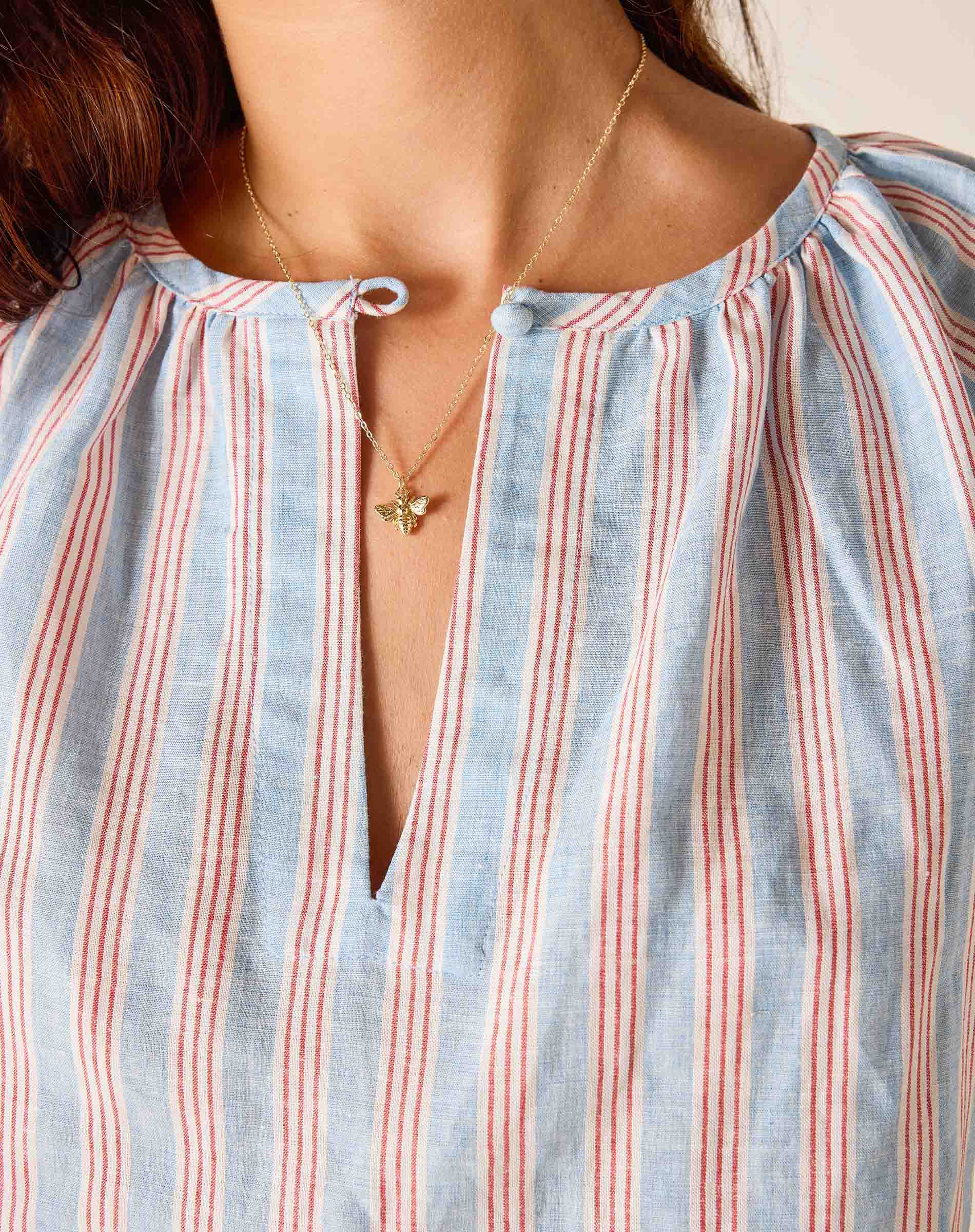 Close-up of a person wearing a striped shirt with a star necklace.