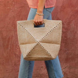 Person holding a woven handbag against a red wall