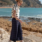Woman standing on a rocky beach with ocean and cliffs in the background