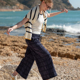 Woman walking on rocks by the ocean with mountains in the background